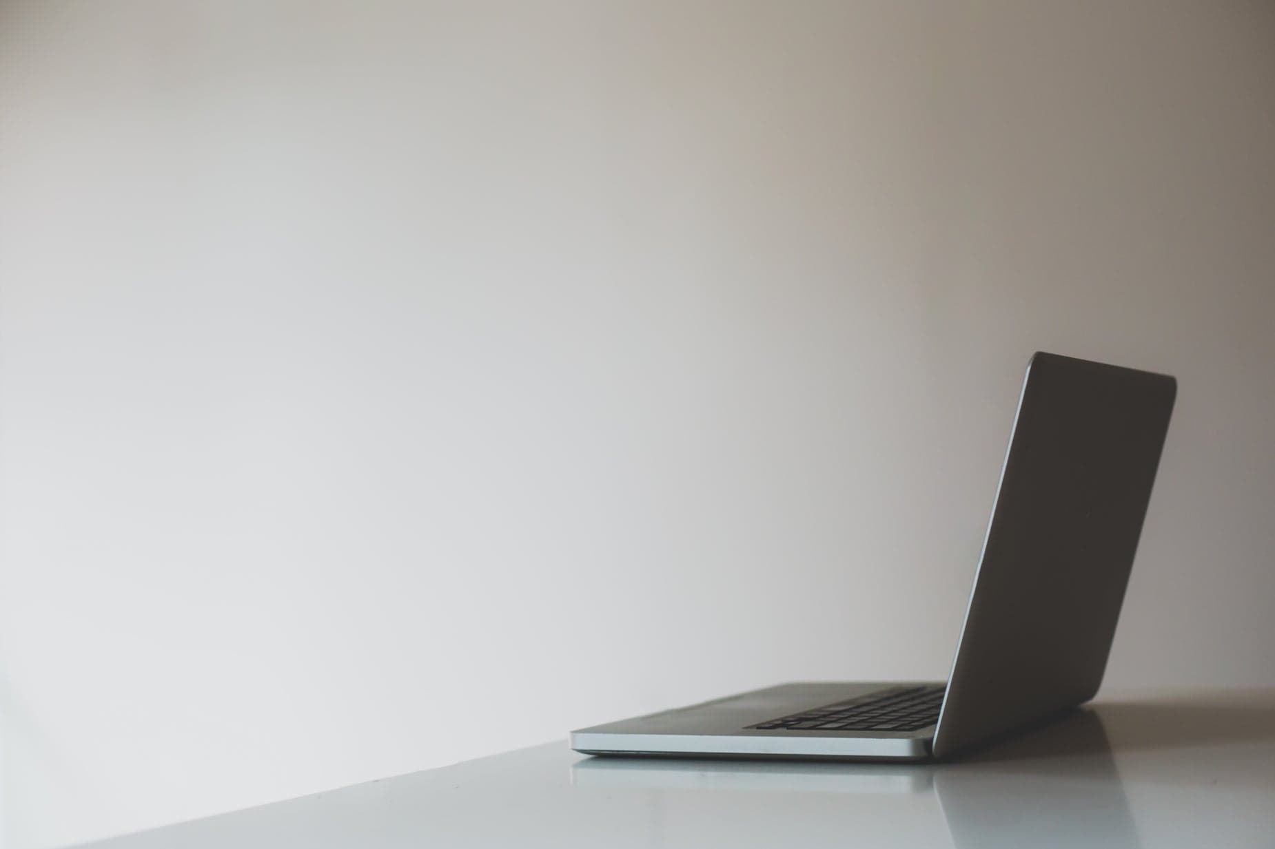 An open laptop sitting alone on a clean desk in an empty, dimly lit office