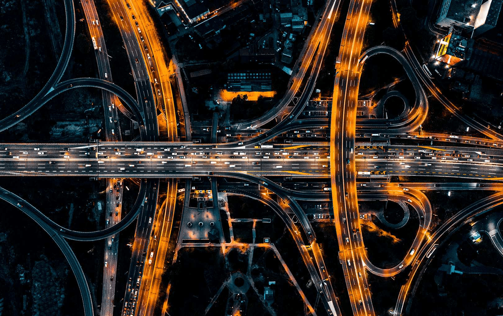 Aerial night photo of a glowing highway interchange, a metaphor for database connections being routed and pooled