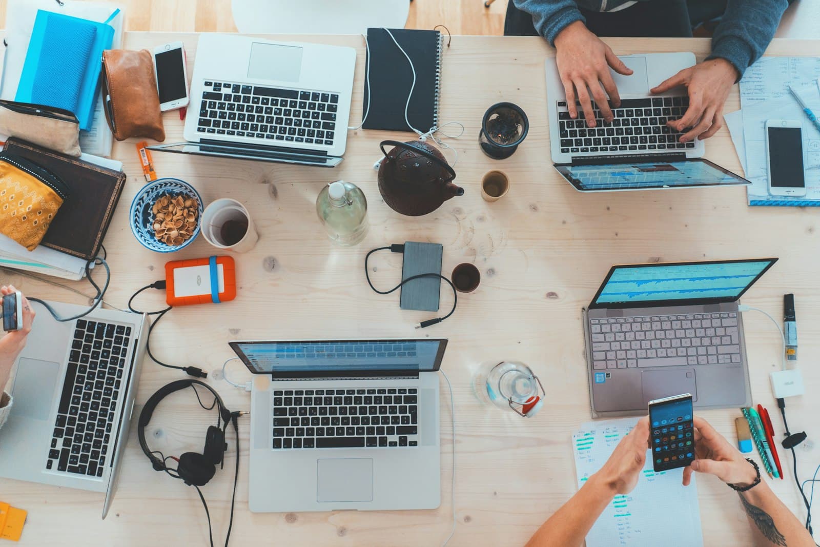 Photo: people collaborating around a wooden table with laptops