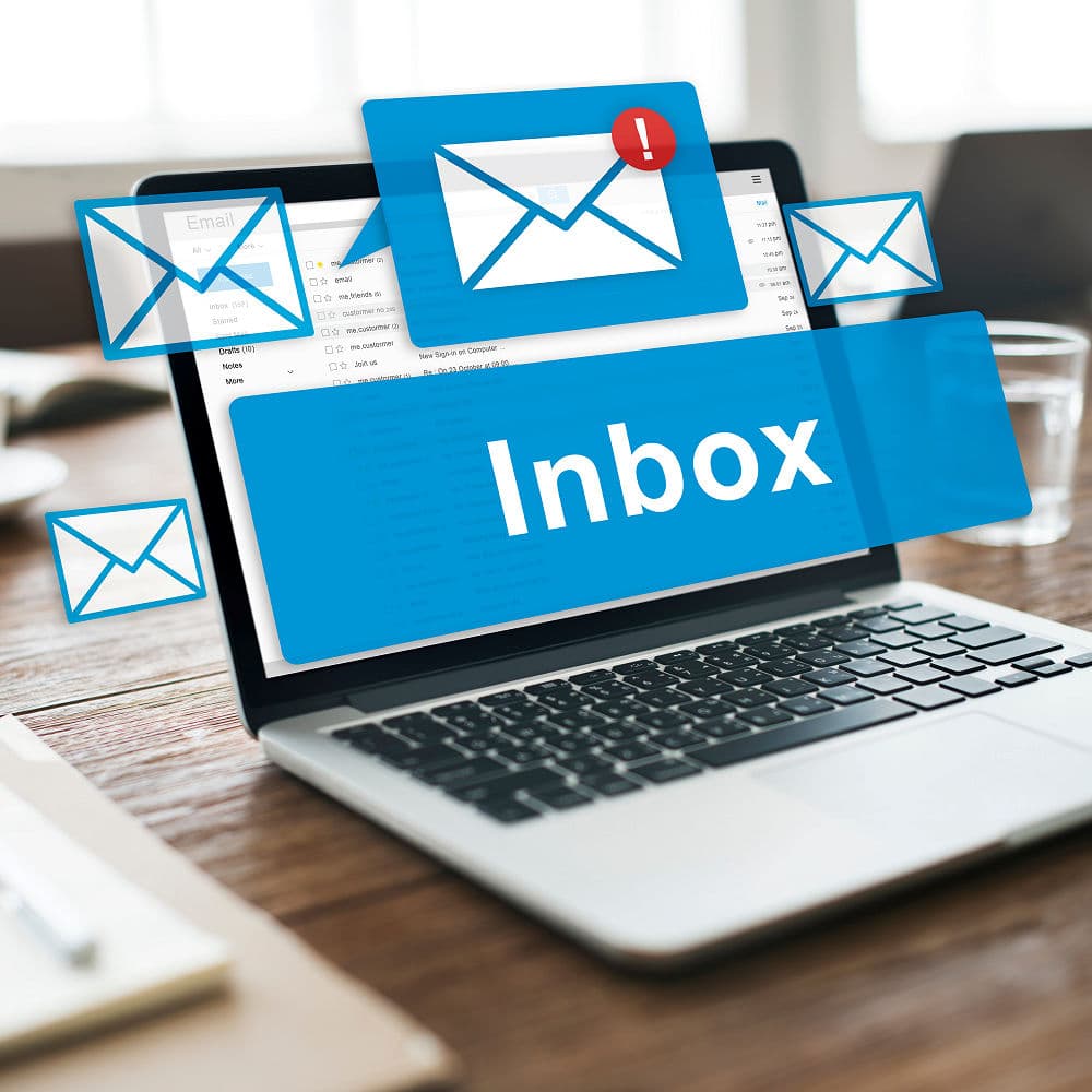 A real photograph of a laptop showing an email inbox, standing in for transactional email that must reach the inbox, not the junk folder.