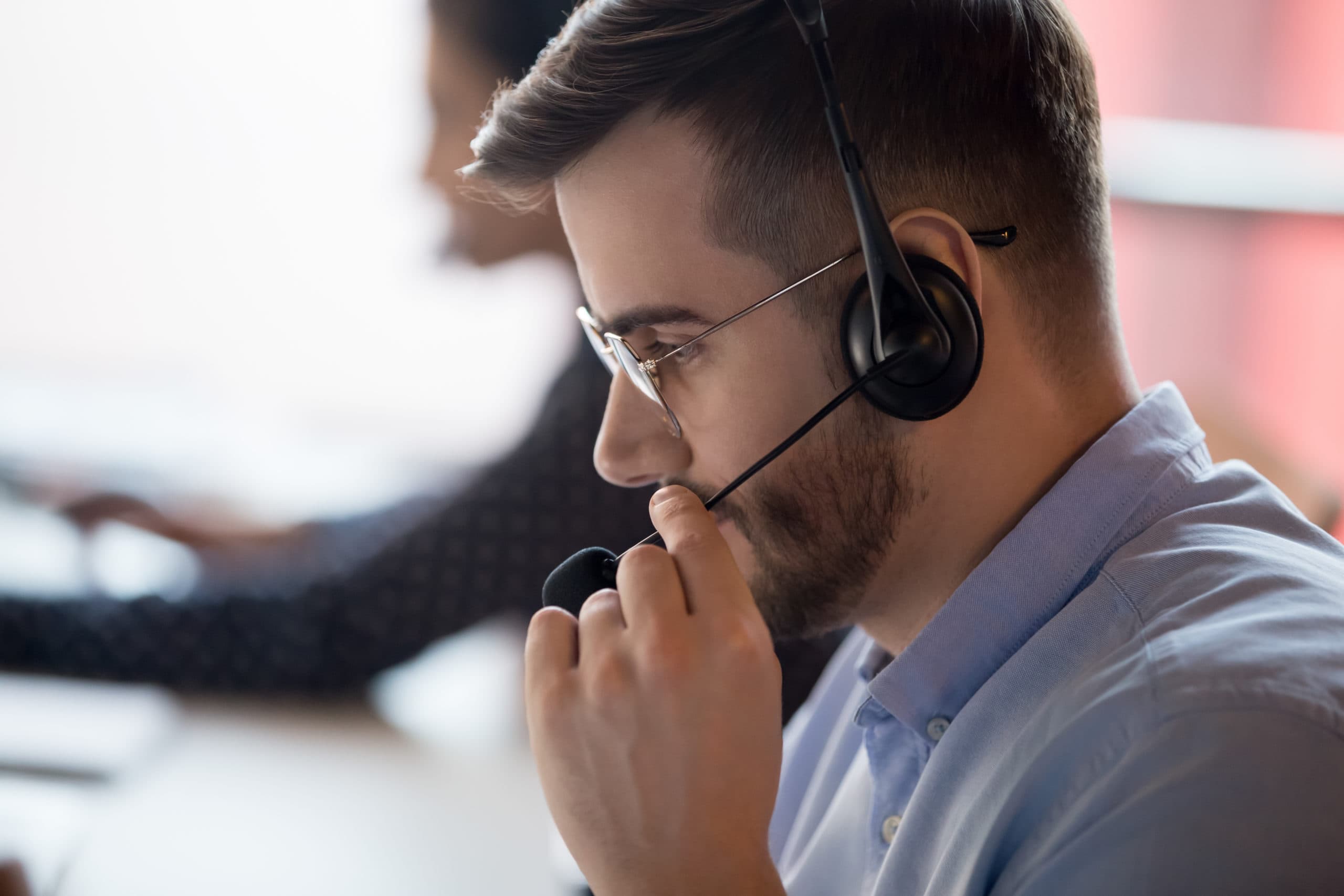 A real photograph of a support worker wearing a headset and speaking into a microphone, standing in for speech-to-speech conversation.
