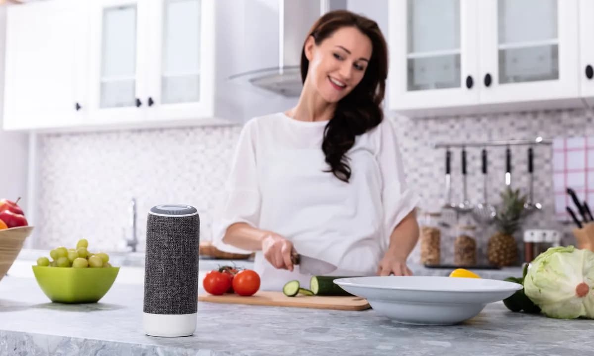 Concept illustration: a laptop on a kitchen counter in voice conversation with a coding agent, code on screen, cooking pots beside it