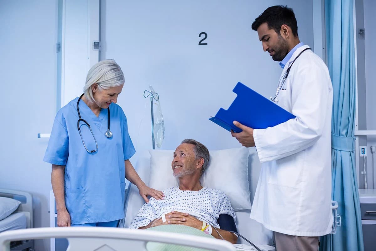 A real photograph of a doctor and a nurse examining a patient's records together in a ward, standing in for a multi-party stepwise diagnostic process.