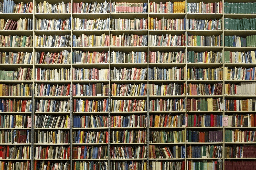 Photo of tall library bookshelves packed with colorful books, a metaphor for a monorepo keeping many packages organized in one place