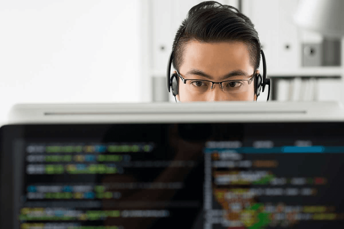 Real photo of a programmer examining code on a monitor