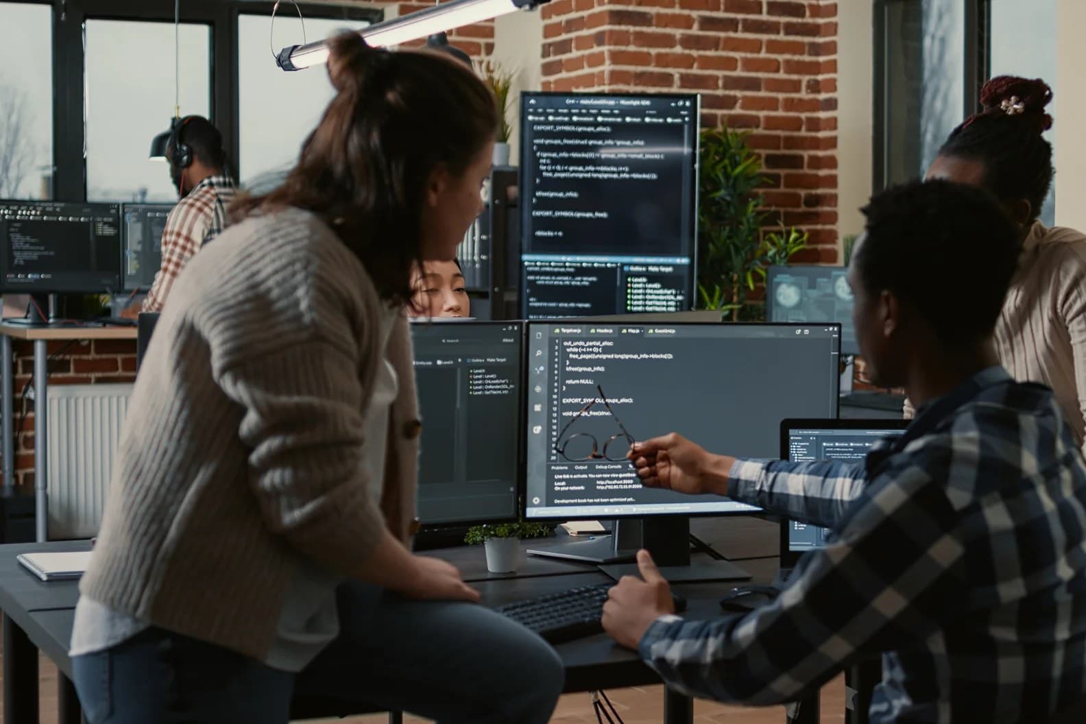 A real photograph of developers gathered around screens showing code in an office; it is not a screenshot of the Microsoft Copilot product interface.