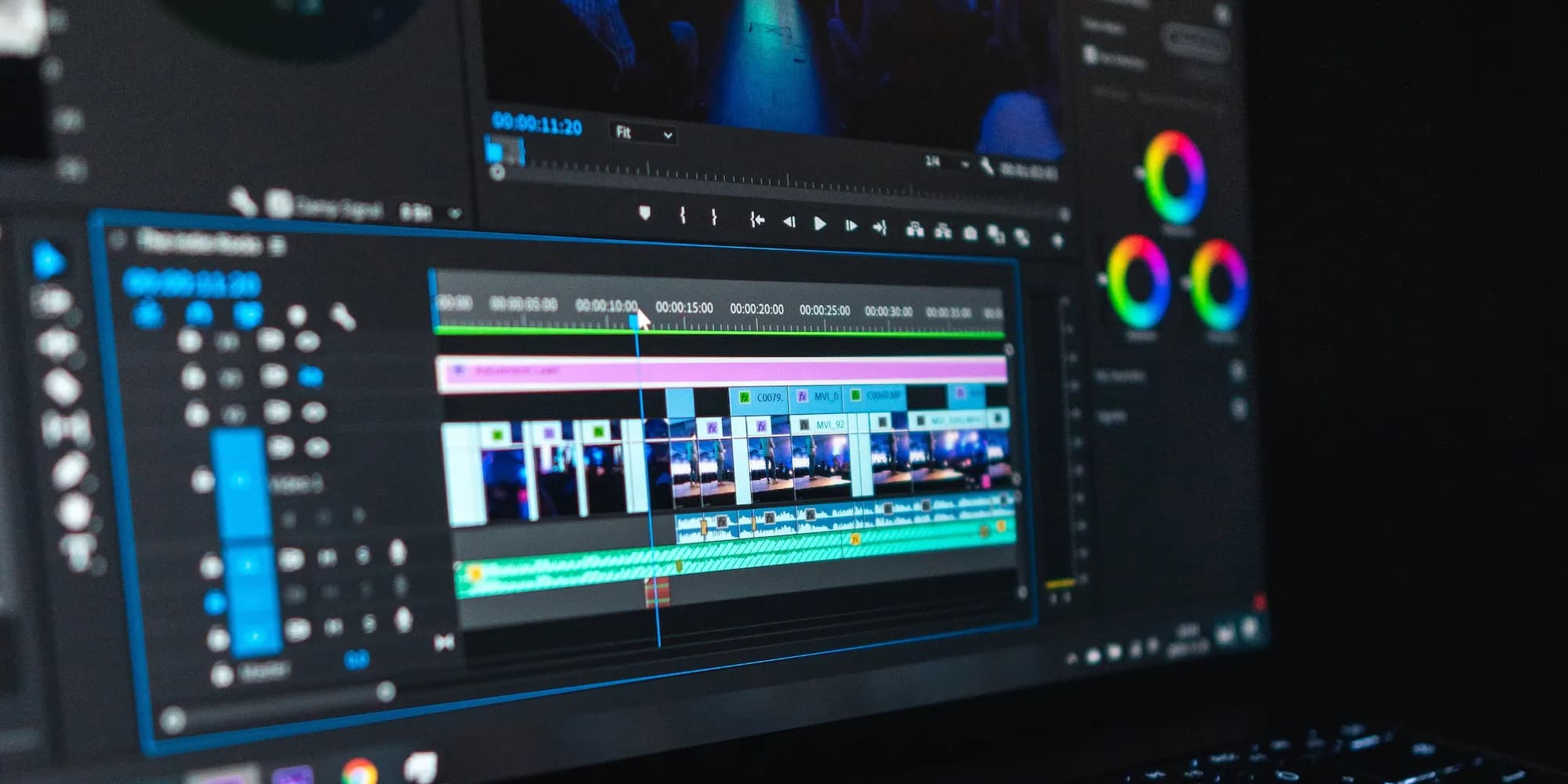 Close-up photo of a video editing timeline on a monitor, with clips, color wheels and timecode visible