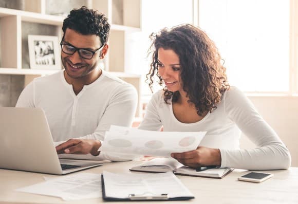 A real photograph of two people reviewing documents together at a laptop, a collaboration metaphor, not a screenshot of Google Docs or any Markdown interface