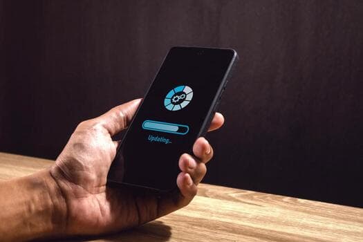 A real photograph of a hand holding a phone showing a software update in progress; it is not a screenshot of the fictional product Egret Check-in.