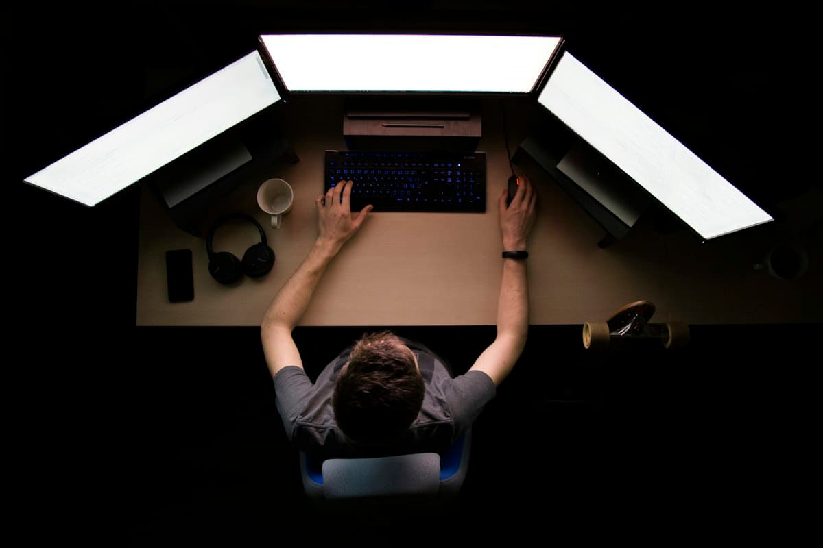 A real overhead photograph of a three-monitor workstation, not a screenshot of any GitHub Copilot interface