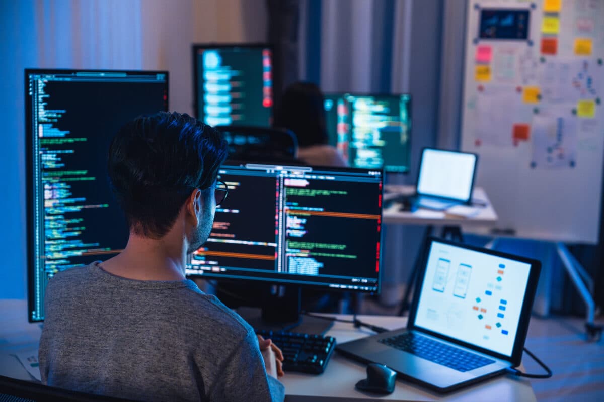 A real photograph of developers working at multiple code screens in an office at night; it is not a screenshot of Bito's product interface.
