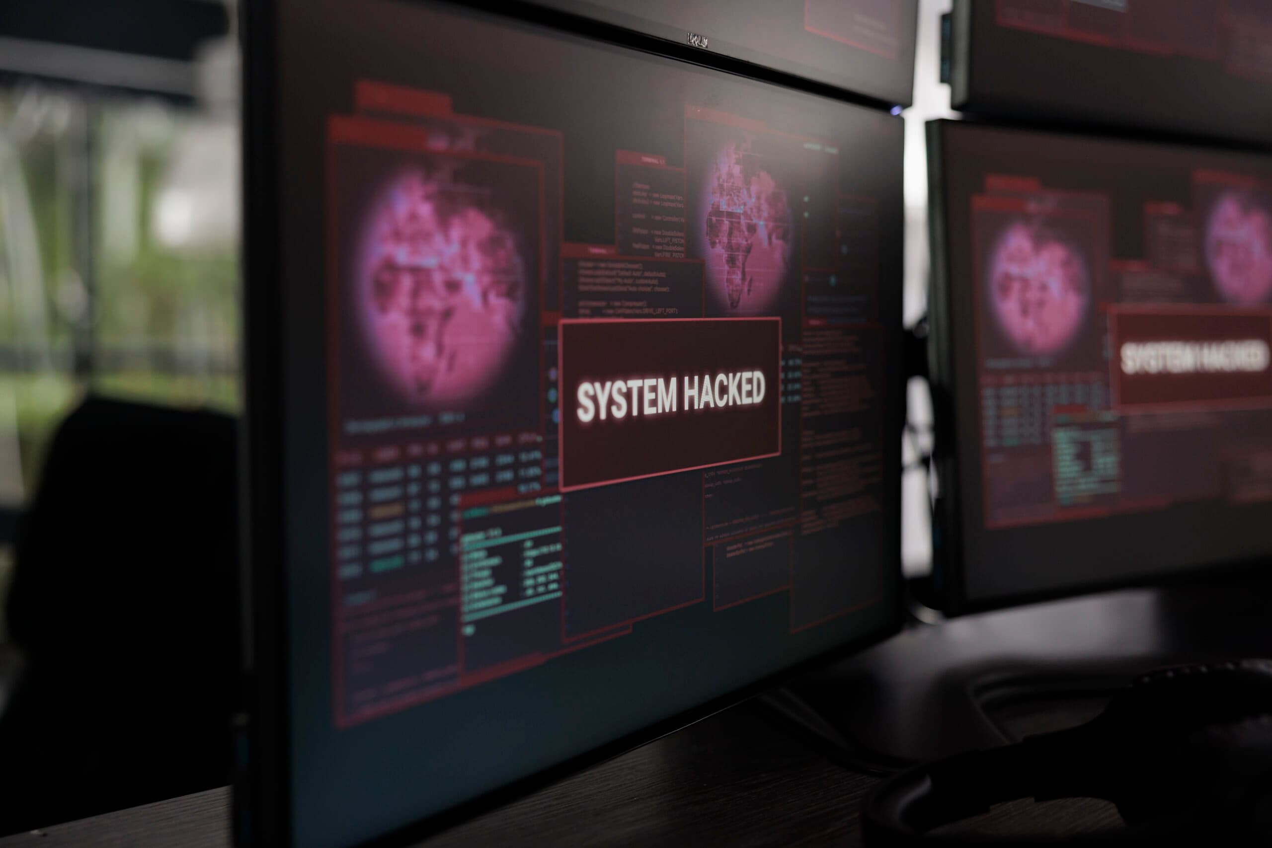 安全运营中心的监控屏幕特写,红色 SYSTEM HACKED 警报