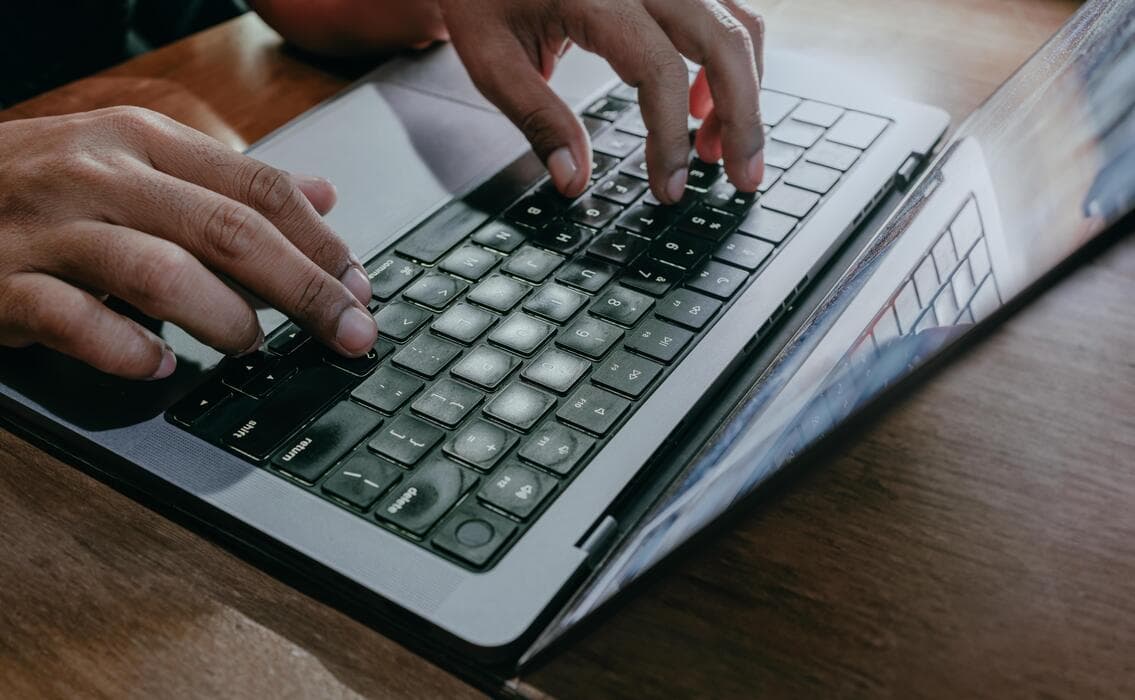 A real photograph of hands typing on a laptop keyboard, an editing metaphor, not a screenshot of any product's undo interface