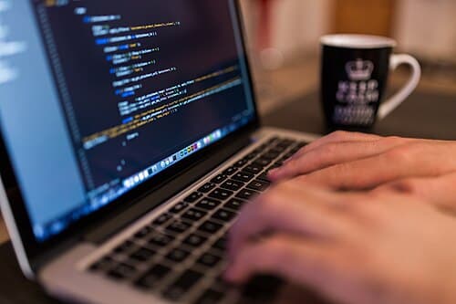 A developer writing code at a computer, with API documentation and a terminal window on screen