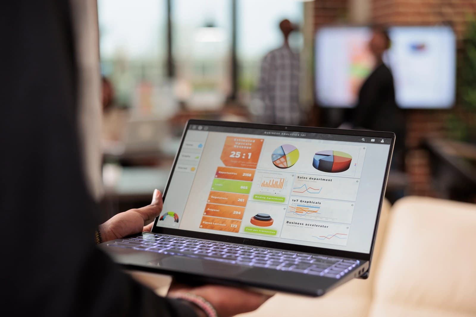 A real photograph of a person holding a laptop showing an analytics dashboard; it is not a screenshot of the fictional product Mountain Wind Guesthouse admin panel.