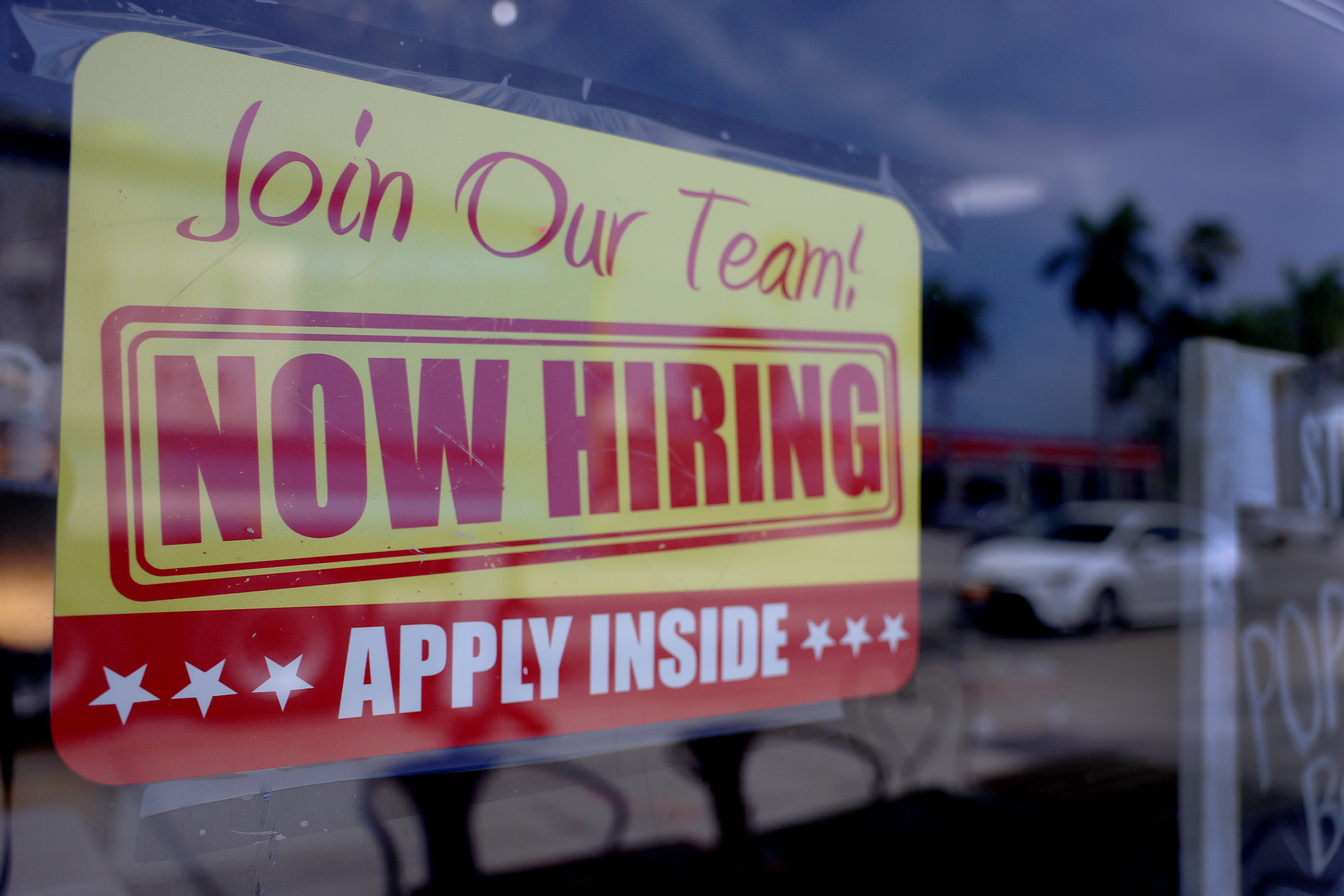 Getty image: a NOW HIRING sign in a shop window — US developer postings rose 15% against the market, but the gains went mostly to senior roles