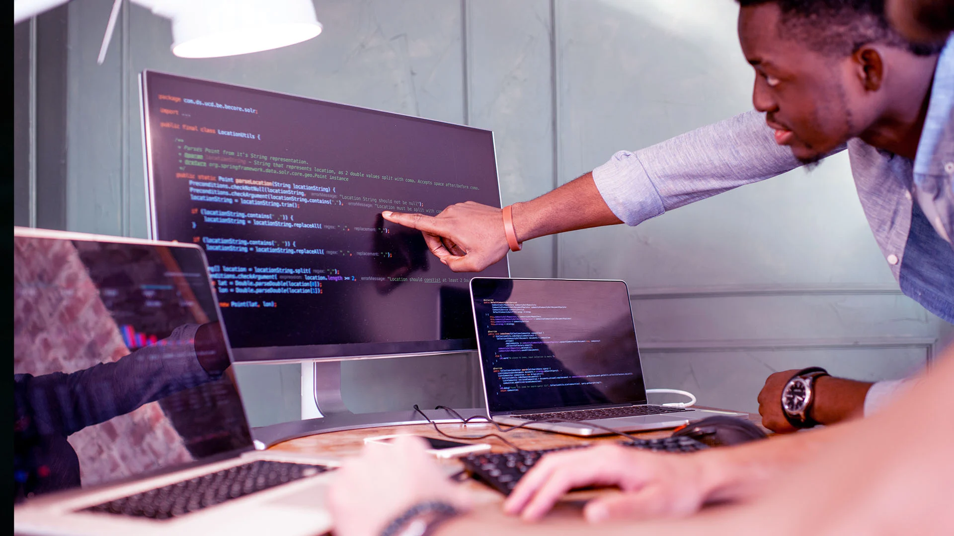 Two developers collaborating around a screen displaying code