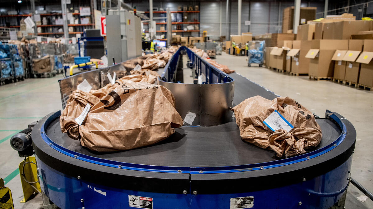 Packages queued on a conveyor belt waiting to be processed, symbolizing a background job queue