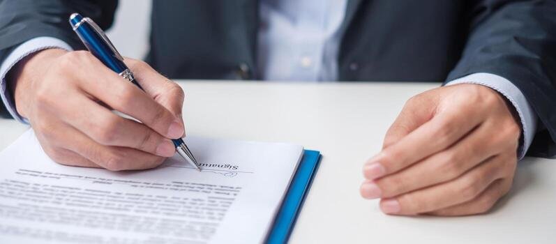 Close-up of a hand signing a contract with a pen