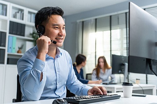 A sales representative with a headset talking to a customer in an office