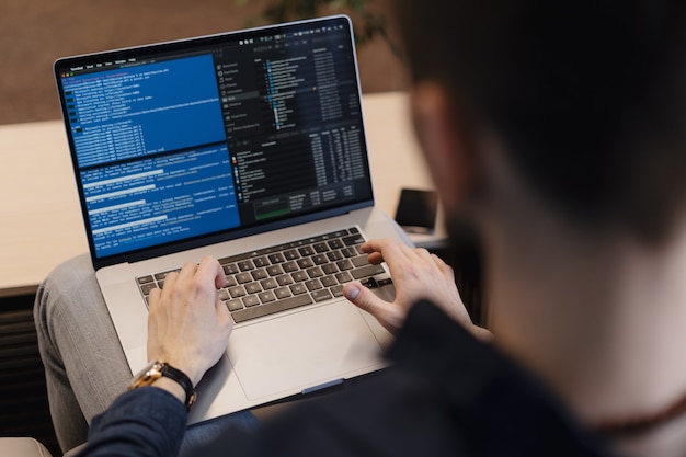 A developer writing code on a laptop: writing code gets cheaper, verification gets more valuable