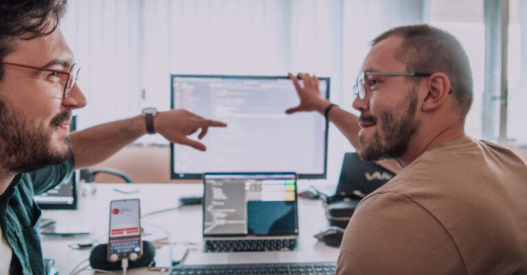 Two developers discussing a code review together; review workload has risen sharply in the AI era